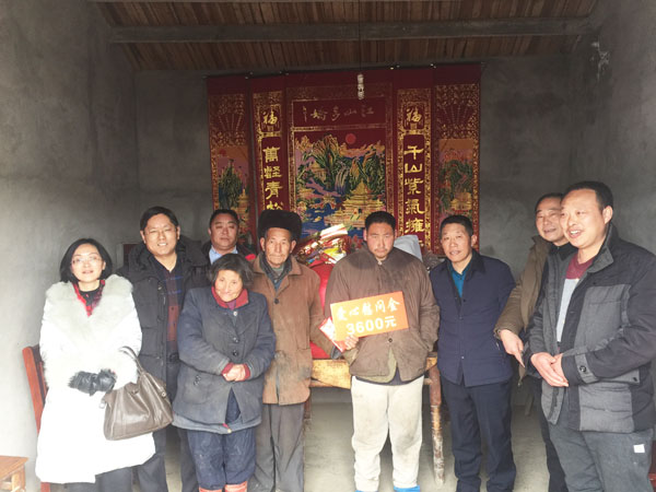 商會會長熊桂祥（左二）、監事會主席李榮杰（右二）和萬盛合作社董事長張世和（左一）、總經理王喜本（右一）帶著慰問團正在慰問張澤俊全家（圖中），并與他們合影留念