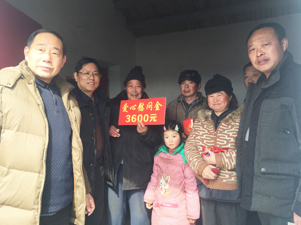 商會愛心尉問團正在慰問張澤家全家（圖中），并與他們合影留念